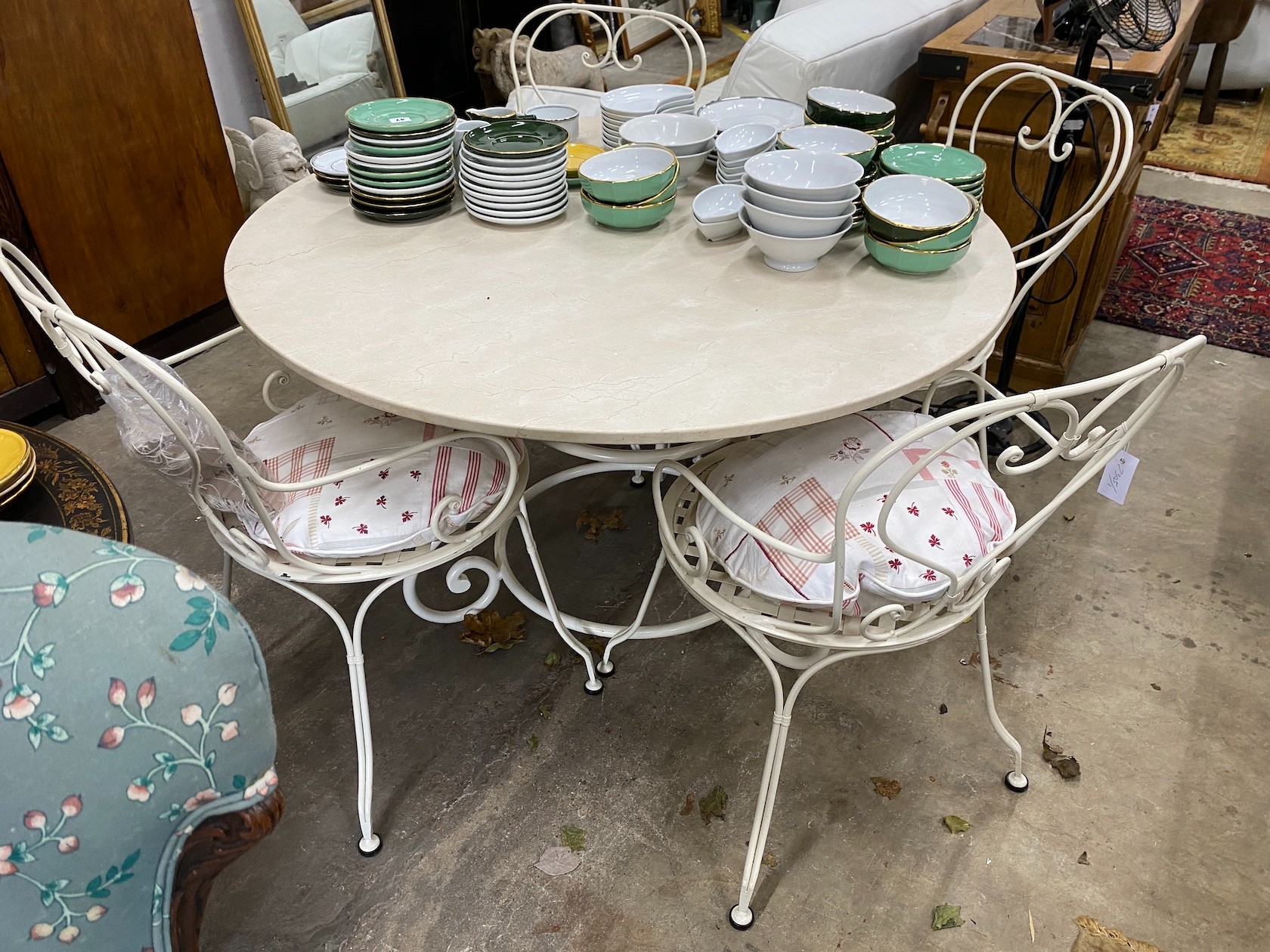 A circular reconstituted marble garden table, diameter 120cm, height 74cm and four painted wrought iron chairs